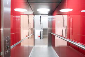  Eine der beiden Stilrichtungen der Aufzüge zeigt rot eingefärbte Glaspaneele und große runde LED-Deckenleuchten in den Eigentumswohnungen 