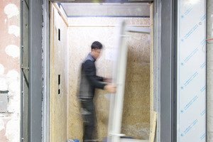 Eine Holzverkleidung schützt die Kabine des Aufzugs im Baubetrieb 