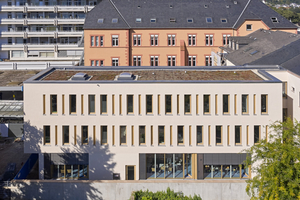  Schmaler, lichtdurchfluteter Riegel: Hofseitig schließt sich der Neubau an das zur Straße orientierte Gebäude (rechts im Bild) mit seinen sensibel gestalteten Räumen für die Rehabilitation an 