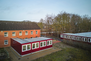  An das zur Wohnunterkunft umgebaute ehemalige Stabsgebäude wurde ein barrierefrei zugänglicher Küchentrakt aus FAGSI Qualitätscontainern angebaut. Daneben ist die neue Wohnanlage platziert  