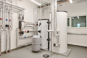  Blick in den Technikraum: Eine modernen Luft-Wärmepumpe mit Pufferspeicher sorgt für effiziente regenerative Beheizung und Kühlung. Zusätzlich wurde eine Photovoltaikanlage auf dem Flachdach installiert, die einen Teil des Gebäude-Energiebedarfs deckt 