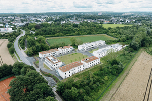  Vier zweigeschossige Wohngebäude und ein Verwaltungsbau gruppieren sich um einen Innenhof zu einem U-förmigen Ensemble 
