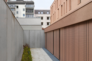  Die monochrome Farbgebung auf allen sichtbaren Fassadenelementen setzt einen charakteristischen Akzent. Die Raffstore-Lamellen in der Sonderfarbe Porphyrrot fügen sich nahtlos in das Konzept ein. 