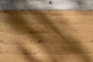  Die Nahaufnahme zeigt eindrucksvoll die besondere Struktur und die unterschiedlichen Schichten der vorgefertigten Stampflehmwand 