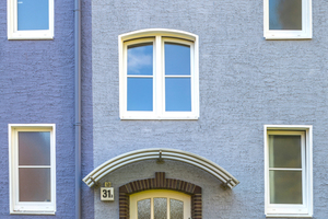  Die weiße Tür wird gerahmt durch die rote Backsteineinfassung und den Sockel. Der starke Hell-Dunkel-Kontrast betont die helle Tür, die optisch zu den weißen Fenstern und Faschen passt 