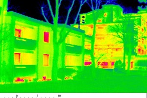  Auf dem Thermografie-Foto sieht man im Vordergrund das sanierte Gebäude. Die Fassade ist gleichmäßig grün. Sie hat annähernd die Temperatur der Außenluft. Im Gegensatz dazu weist  das unsanierte Gebäude rechts im Hintergrund mehr Rottöne auf. Es ist deutlich wärmer als die Außenluft, eine Folge der hohen Wärmeverluste 