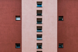  Ein vorspringendes, in hellem Rot gefasstes Treppenhaus mit einem vertikalen Band kleiner quadratischer Fenster 