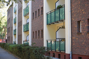  Die rustikale Optik von Flachverblendern, heller Putz und grün schimmernde Balkonbrüstungen aus Glas prägen das Erscheinungsbild der Fassade dieses sanierten Wohngebäudes in Hamburg 