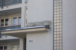  Im Spritzwasserbereich des nicht geneigten Vordachs kommt es zu deutlichen Verunreinigungen. Der Rest der Fassade ist nicht betroffen 