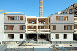  Der Holzbau ist im dreigeschossigen, hofseitigen Bauteil an der Fassade ablesbar. Die vertikale Holzverschalung transportiert die tragende Struktur an die Außenhaut 