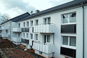  Südseite der beiden Mehrfamilienhäuser mit der neu gedämmten Fassade und den integrierten Solar‑Luft-Kollektoren unter den Fenstern zum Wohnbereich<br /> 